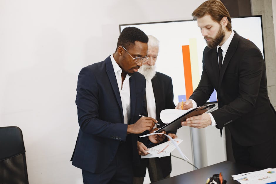 Three businessmen engaged in document signing in a modern office setting.